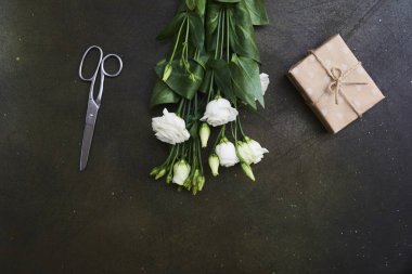 Bahar beyaz eustoma çiçek ve hediye kutusu üzerinde koyu arka plan, sizin metin için yer ile tebrik kartı. Üstten Görünüm