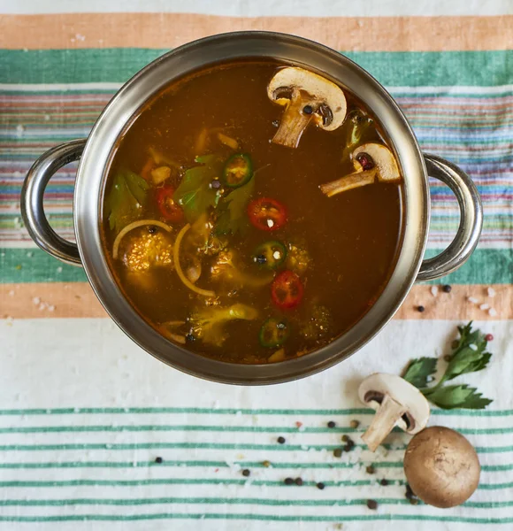 Top view of homemade soup with vegetables and mushrooms in metal pan