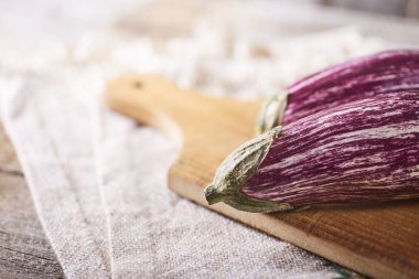 Mutfak havlusu ahşap rustik arka plan üzerinde üzerinde kesme tahtası üzerinde taze sağlıklı patlıcan. Metin için yer