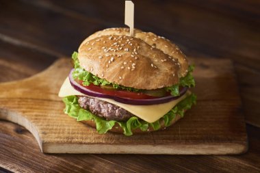Kesme tahtası ahşap arka plan üzerinde taze lezzetli burger