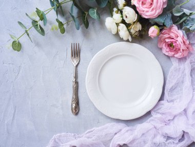 Yuvarlak boş tabak çatal ve beton arka plan üzerine güzel çiçekler. Üstten Görünüm