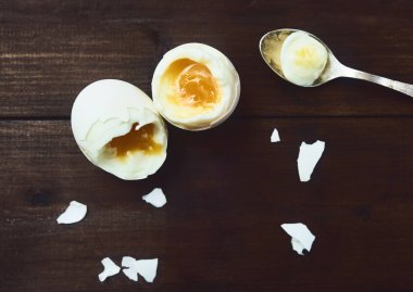 Lezzetli yumuşak haşlanmış yumurta ve kaşık koyu kahverengi ahşap rustik arka plan üzerinde