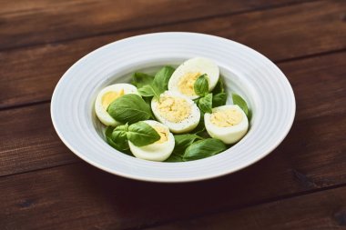 Haşlanmış yumurta ve taze fesleğen ile lezzetli salata tabağına koyu kahverengi ahşap rustik arka plan üzerinde bırakır..