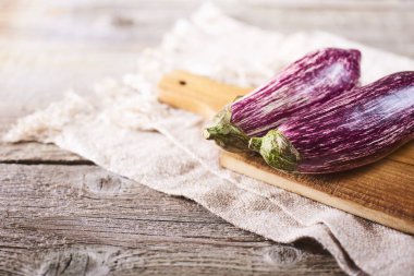 Mutfak havlusu ahşap rustik arka plan üzerinde üzerinde kesme tahtası üzerinde taze sağlıklı patlıcan. Metin için yer