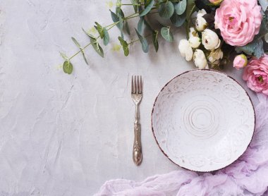 Yuvarlak boş tabak çatal ve beton arka plan üzerine güzel çiçekler. Üstten Görünüm