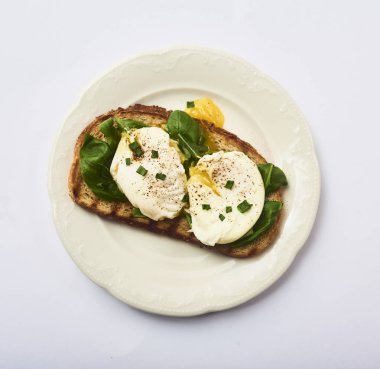 Beyaz arka plan üzerinde izole beyaz tabak taze fesleğen ile tost lezzetli haşlanmış yumurta bırakır