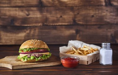 Kesme tahtası ile ile patates kızartması, ketçap ahşap arka plan üzerinde taze lezzetli burger