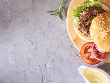 Taze lezzetli hamburger hazırlanması. Yeşil çiğ sebze ve beton zemin üzerine buns