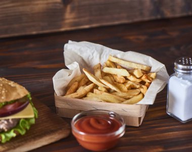 Kesme tahtası ile ile patates kızartması, ketçap ahşap arka plan üzerinde taze lezzetli burger