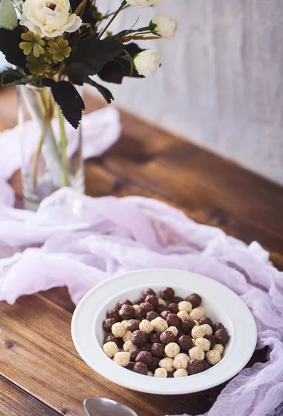 Cereais Chocolate Tigela Branca Flores Vaso Sobre Fundo Madeira Marrom — Fotografia de Stock