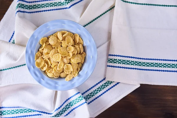 コーンフレークやキッチン タオルと木製の背景ブルーのボウルの穀物 トップ ビュー — ストック写真