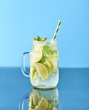 Mojito kokteyl limon ve nane cam kavanozlar. Mavi ayna arka plan.