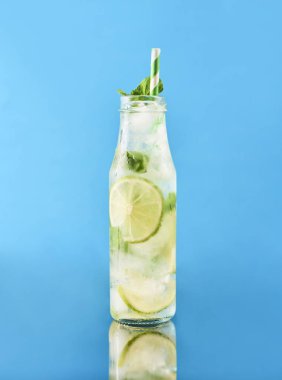 Mojito limes ve cam şişe içinde nane kokteyli. Mavi ayna arka plan.