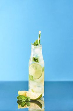 Mojito limes ve cam şişe içinde nane kokteyli. Mavi ayna arka plan.