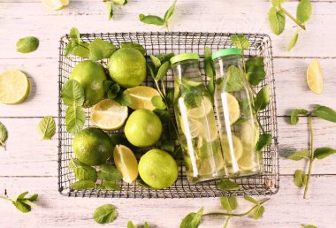 Mojito kokteyl limon ve nane metal sepet beyaz tahta masada yatan cam şişelerde. Üstten Görünüm