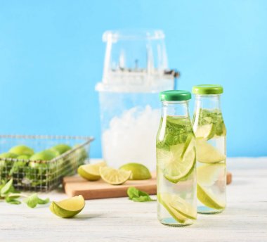Mojito kokteyl limon ve nane Beyaz ahşap masa üzerinde cam şişelerde. Mavi arka plan