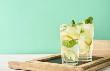 Mojito limes ve ahşap masa üzerinde highball bardaklarda nane kokteyli. Turkuaz arka plan
