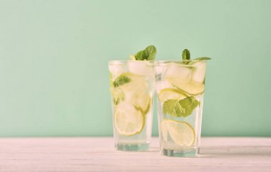 Mojito limes ve ahşap masa üzerinde highball bardaklarda nane kokteyli. Turkuaz arka plan
