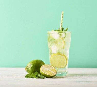 Mojito limes ve ahşap masa üzerinde highball bardaklarda nane kokteyli. Turkuaz arka plan