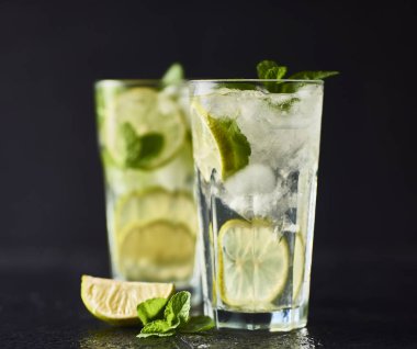 Mojito limes ve highball gözlük karanlık taş zemin üzerine nane kokteyli.