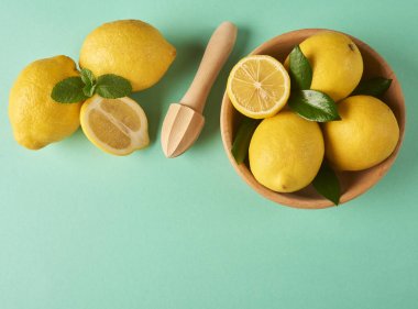 Metin alanı olan turkuaz arka plan üzerinde ahşap kase taze sarı limon