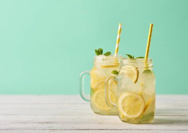 Mason kavanoz turkuaz arka plan üzerinde ahşap masa üzerinde taze lezzetli limonata