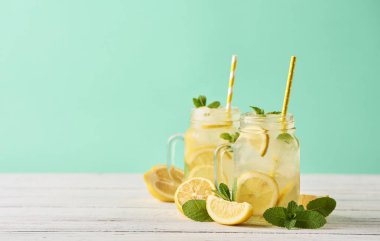 Mason kavanoz turkuaz arka plan üzerinde ahşap masa üzerinde taze lezzetli limonata