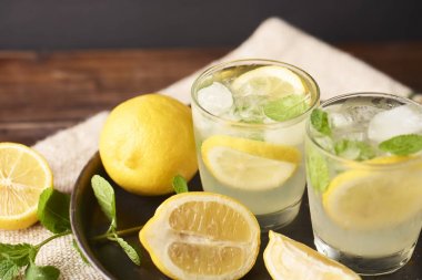 Koyu arka plan üzerinde bardaklarda taze lezzetli limonata.