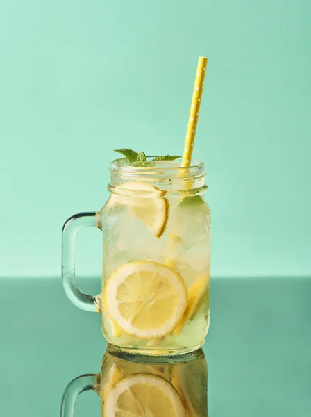 Fresh tasty lemonade in mason jar glass on turquoise background