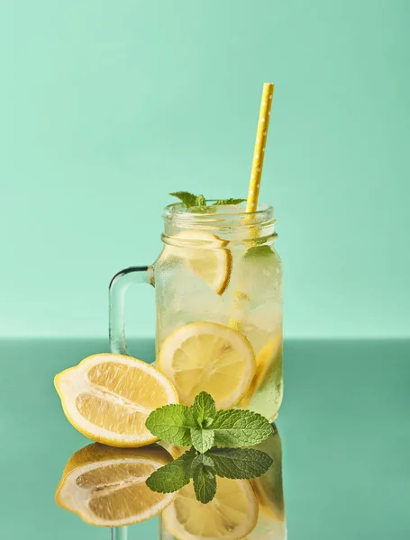 Fresh tasty lemonade in mason jar glass on turquoise background
