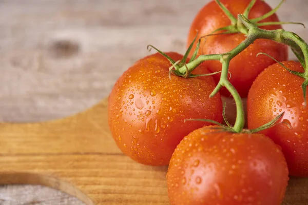 Frische rohe Tomaten vor hölzernem Hintergrund — Stockfoto