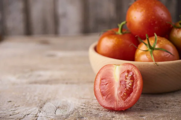 Frische rohe Tomaten vor hölzernem Hintergrund — Stockfoto