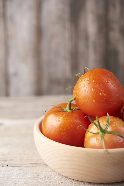 Frische rohe Tomaten vor hölzernem Hintergrund — Stockfoto