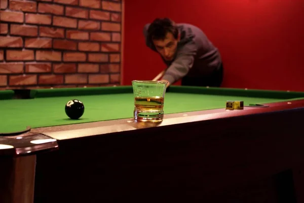 Pool billiard game. Closeup of whisky glass on the billiard pool