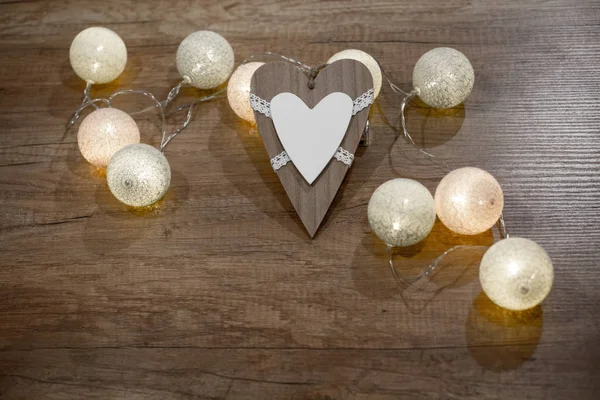 Decoratieve handgemaakte hart met meerkleurige lampjes op de houten tafel — Stockfoto