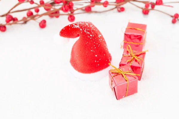 Santa hat on snow with some gifts — Stock Photo, Image