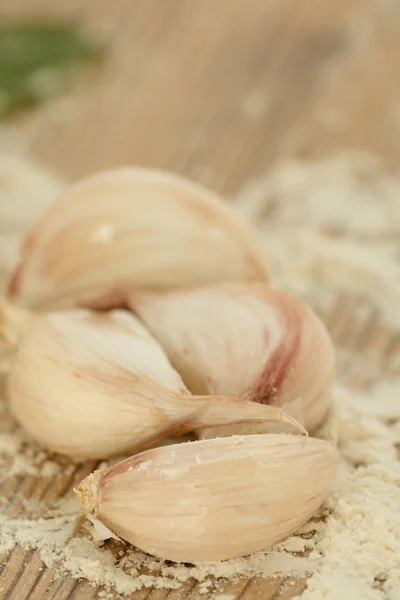 Garlic cloves on table with flour — Stock Photo, Image