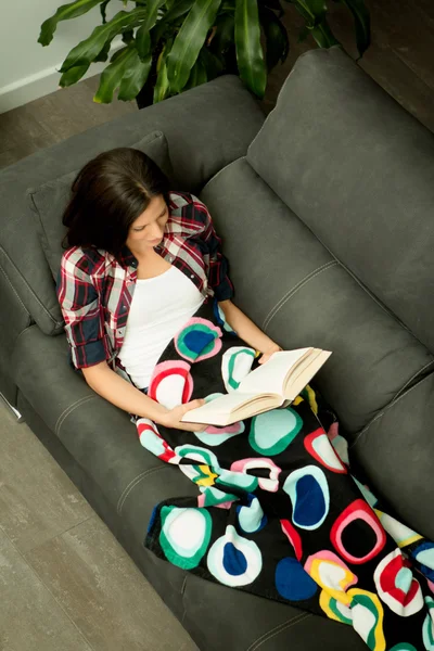 Brunette girl reading on sofa — Stock fotografie