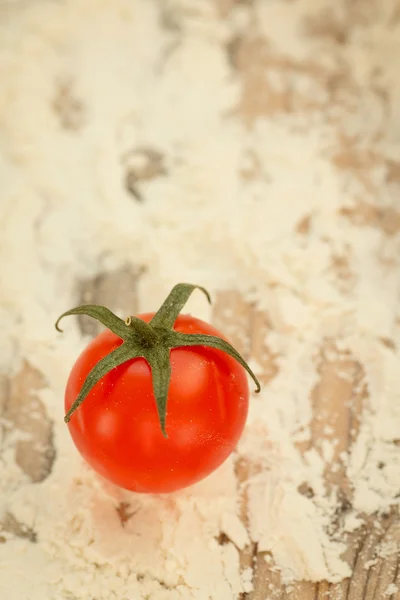 Cherry tomato on table with flour — Stock Photo, Image