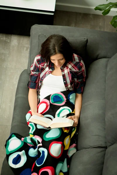 Brunette girl reading on sofa Royalty Free Stock Photos