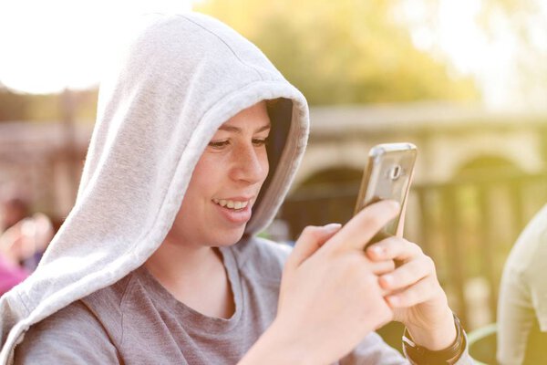 hooded teenager with smartphone