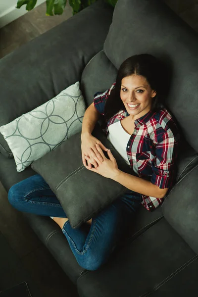 Brunetka dziewczyna siedzi na kanapie — Zdjęcie stockowe
