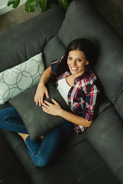 Brünette mädchen sitzen auf sofa — Stockfoto