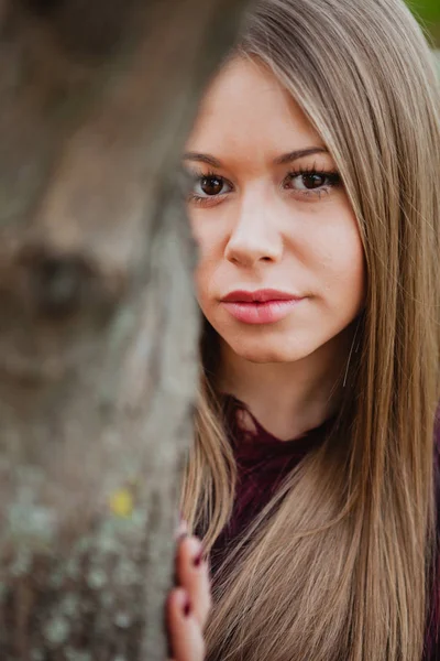 Menina loira ao lado de tronco de árvore — Fotografia de Stock