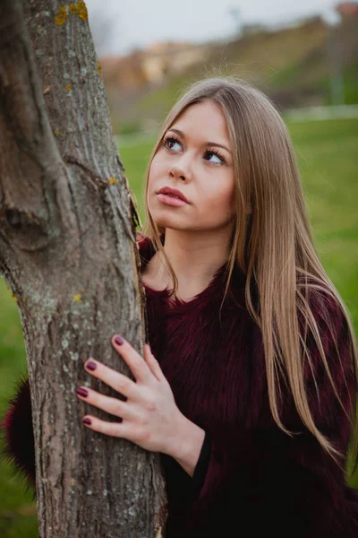 Ξανθιά κοπέλα δίπλα σε κορμό δέντρου — Φωτογραφία Αρχείου