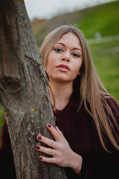 Menina loira ao lado de tronco de árvore — Fotografia de Stock