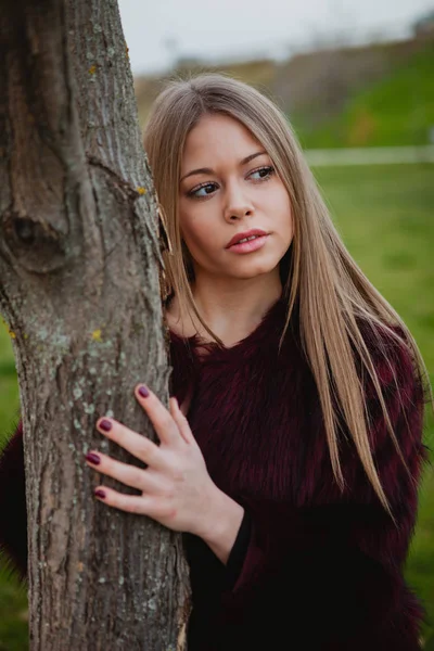 Ragazza bionda accanto al tronco d'albero — Foto Stock