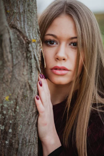 Ragazza bionda accanto al tronco d'albero — Foto Stock