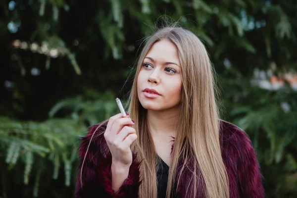 Κορίτσι με μακριά μαλλιά καπνιστές στο πάρκο — Φωτογραφία Αρχείου