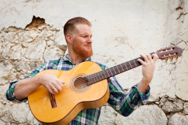 Kızıl saçlı sakallı adam gitar ile